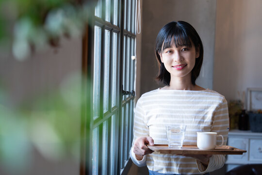 お店でコーヒーを持って笑っている女性