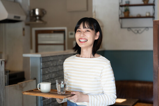 お店でコーヒーを持って笑っている女性