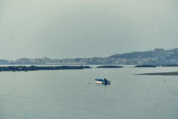Obraz premium Small boat floating on sea with coastal town
