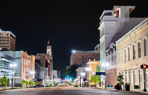 Scenic night view of the illuminated historic buildings and the Lamar Life clock tower along empty Capitol Street in downtown Jackson, Mississippi, USA