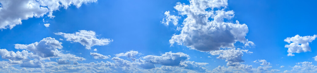 A high-resolution image showcasing a vibrant blue sky filled with scattered white cumulus clouds. The natural daylight highlights the soft textures of the clouds.