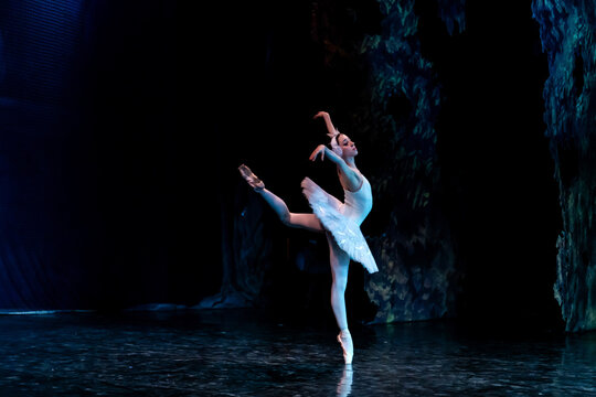 Woman ballerina performing on stage in ballet performance.