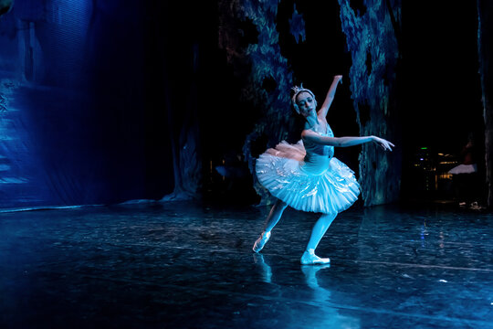 Woman ballerina performing on stage in ballet performance.