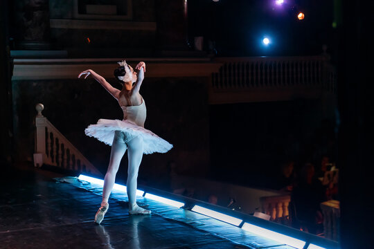 Ballet soloist in white tutu bowing on stage toward audience