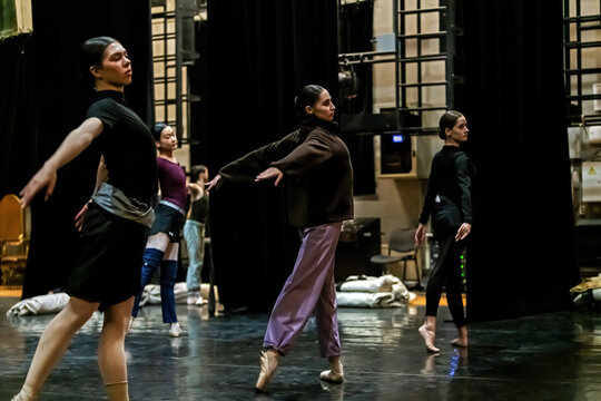 ballerinas in warm-up clothes rehearsing on stage, from side backstage