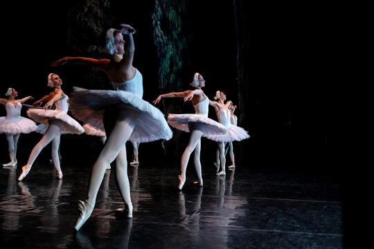 group of women ballet dancers performing on stage in white tutus.