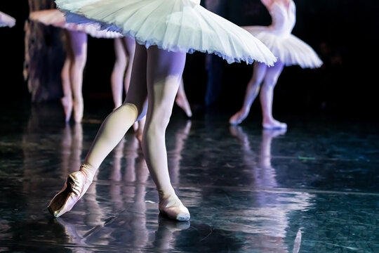 Woman ballerina performing on stage in a white tutu.