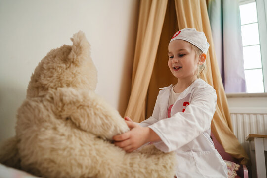 Little girl playing doctor caring for her toys at home