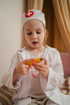 Preschool girl in medical costume caring for her toys patient