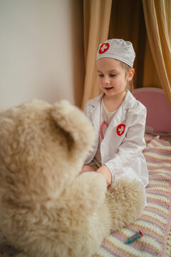 Little girl in doctor costume pretending to treat her toys