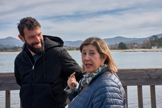 Mother and adult son chatting amiably by the sea on a sunny day at Ladeira Beach