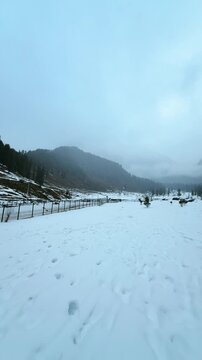 4K Vertical POV shot of girl legs walk on snow and showing beautiful winter mountain view at Aru Valley, Jammu and Kashmir, India. Travel and vacation background. Exploring new places by solo travelli
