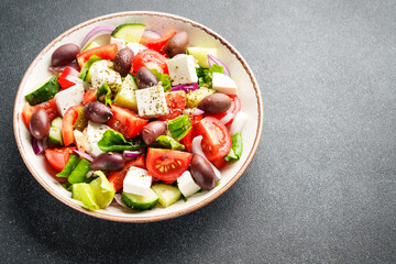 Greek salad in craft plate on black kitchen table.
