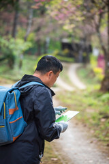 Fototapeta premium Vertical image Asian man use professional digital camera take a photo. Smiling male photographer look at photo film camera outdoors. Man shooting photo in green nature park. Men hobby lifestyle