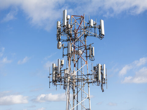 Aerial view of a cell phone tower piercing the vibrant blue sky with puffy white clouds, a modern structure against nature's backdrop, Hollywood, Florida, United States.