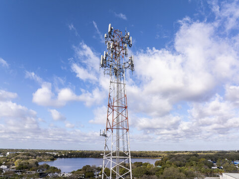 Aerial view of a towering cell phone tower piercing the vast blue sky, a modern sentinel amidst the urban landscape, Hollywood, Florida, United States.