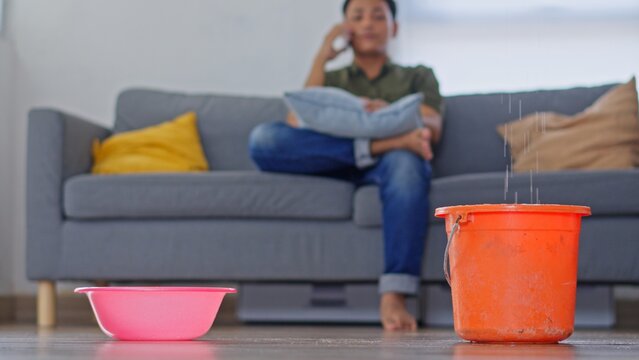 Close up of Man Looking up and Calling for Help While Holding Bucket Under Ceiling Leak