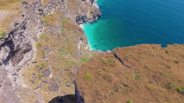 Aerial view of steep limestone cliffs overlooking turquoise ocean water and rocky coastline in Salalah, Dhofar region, Oman.