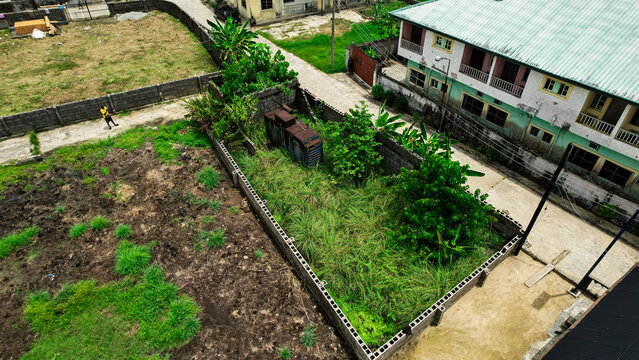 Aerial view of a walled compound with overgrown vegetation amidst buildings, capturing the essence of urban nature, Abonnema, Rivers, Nigeria.