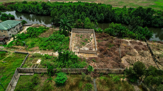 Aerial view of a landscape with a mix of vibrant green vegetation, bare earth, and built structures, creating a textured mosaic of colors, Abonnema, Rivers, Nigeria.
