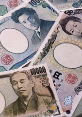 Japanese yen money bills pile on table. Japan banknotes of JPY currency close up. © Larysa