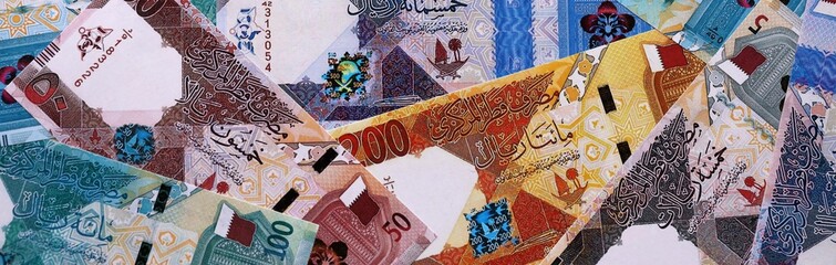 Qatari riyal money bills pile on table. Qatar banknotes of QAR currency close up.