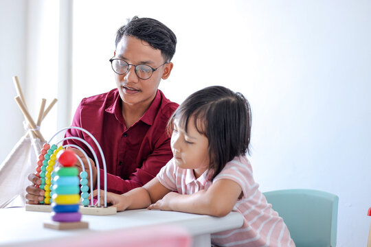 Young Asian Man And Little Girl Playing Colorful Educational Toys Together
