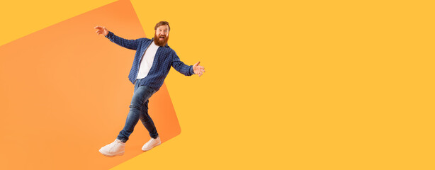 A man is dancing with joy in a bright room. He wears casual clothes and has a beard. The background...