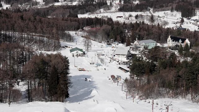 Winter scene looking down at a ski area with terrain park features and forest