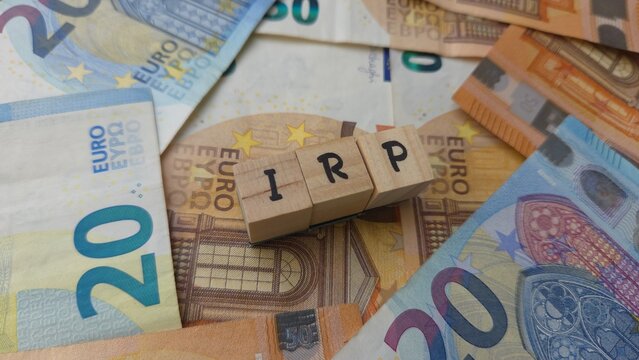 IRP acronym made of wooden letter cubes on pile of Euro banknotes. Individuele Pensioen Spaar (Individual Pension Savings)