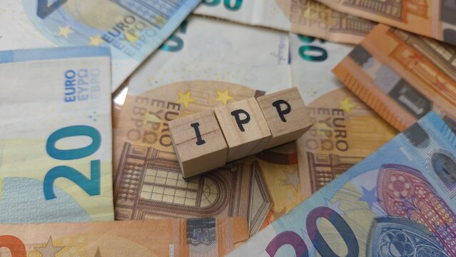 IPP acronym made of wooden letter cubes on pile of Euro banknotes. Imp&ocirc;t des Personnes Physiques (Individual Income Tax)
