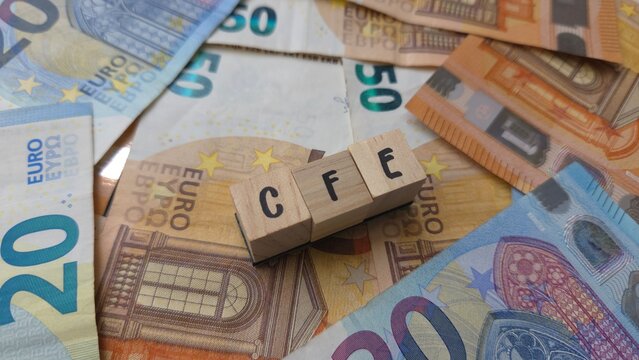 CFE acronym made of wooden letter cubes on pile of Euro banknotes. Cotisation Fonci&egrave;re des Entreprises (Business Property Tax)