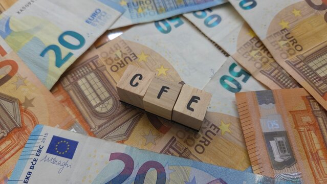 CFE acronym made of wooden letter cubes on pile of Euro banknotes. Cotisation Fonci&egrave;re des Entreprises (Business Property Tax)