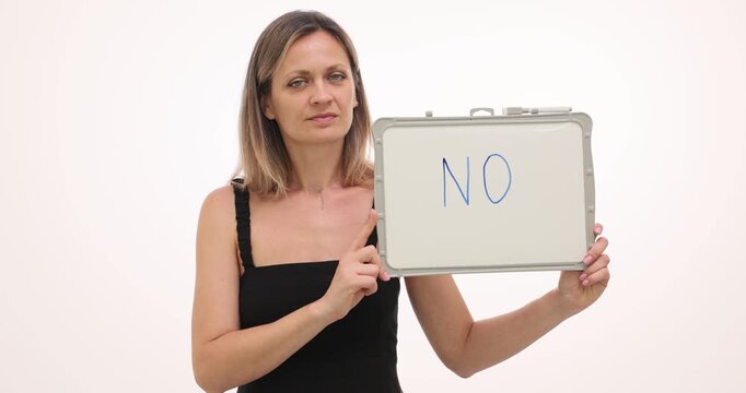 Woman holds whiteboard showing word No in bold letters. Lady in cocktail dress grips frame presenting refusal message with steady serious expression