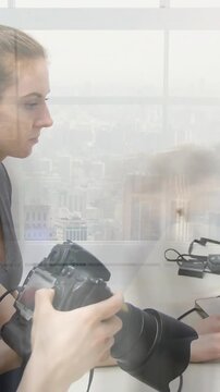 Vertical video: Woman operator checking DSLR, blurred coworker crossing revealing laptop, prepping