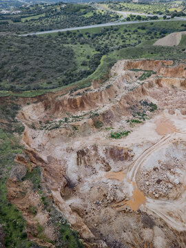 Aerial view of an open quarry, the earth's raw textures exposed in layered patterns, revealing a landscape transformed by industry, Alvor, Faro District, Portugal.