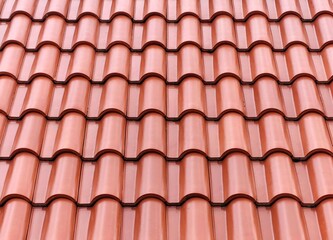 Background view of red terracotta interlocking s-shape clay roof tiles in a repetitive pattern.