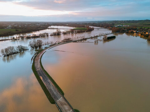 Cadillac-sur-Garonne, France - 20 February 2026: Aerial view of a landscape where floodwaters envelope roads and fields, reflecting the muted sky in a somber, watery expanse.