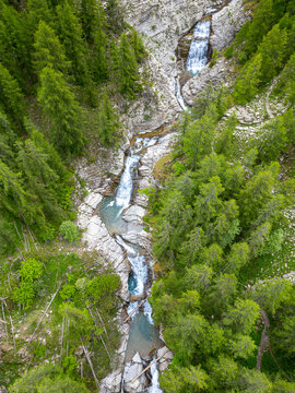 Aerial view of a cascading river slicing through a vibrant green forest, creating a striking contrast of nature's raw power and serene beauty, Vasques de la Lance, Provence-Alpes-Cote d'Azur, France.