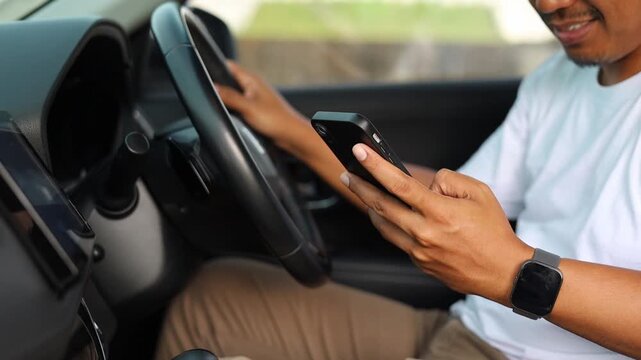 Close up unknown Asian man driver car owner inside automobile typing message using mobile phone smartphone chatting social media app communication