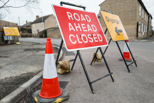 Typical road work signs seen on a road junction in Britain. The road is closed due to flooding following heavy rains.