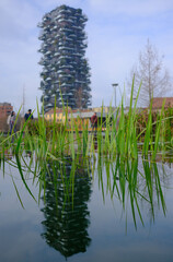 View of Bosco Verticale residential towers reflected on water surface in the modern Porta Nuova district, contemporary architecture and urban skyline.