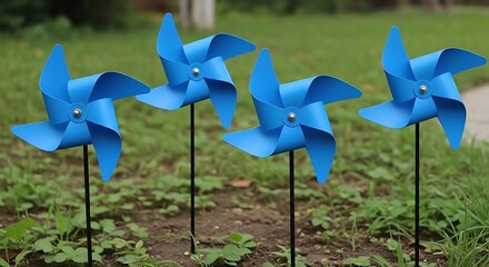 Four blue pinwheels in a garden green grass black sticks