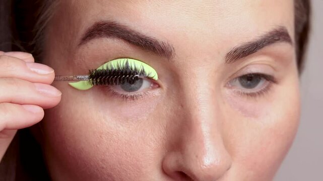 Blue eyes caucasian woman twists her eyelashes on her own. A woman laminates eyelashes, comb lashes on a silicone roller. close up footage