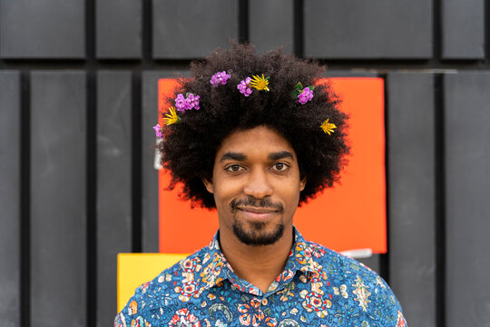 Portrait of man with blossoms in his hair wearing colorful shirt