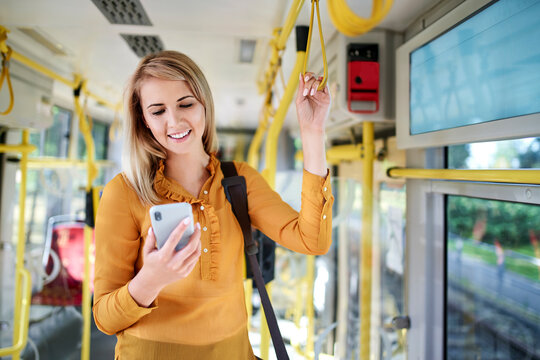 Smiling young woman using smartphone in a tram