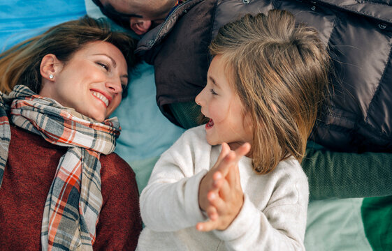 Happy girl with her family on blanket clapping hands