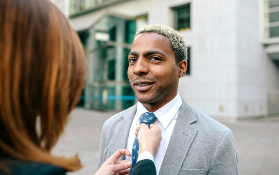 Young businesswoman fastening tie of young businessman