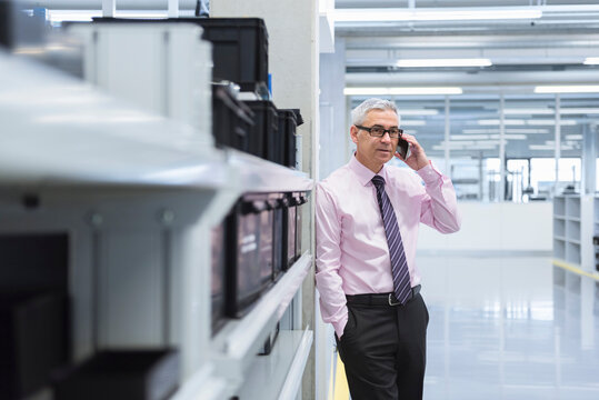 Manager on shop floor of a factory using smart phone