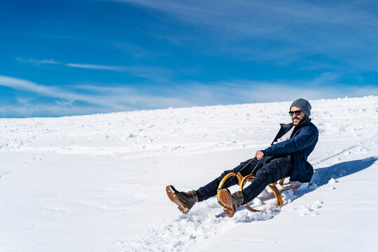 Germany, Bavaria, Brauneck, man sledging in winter in the mountains